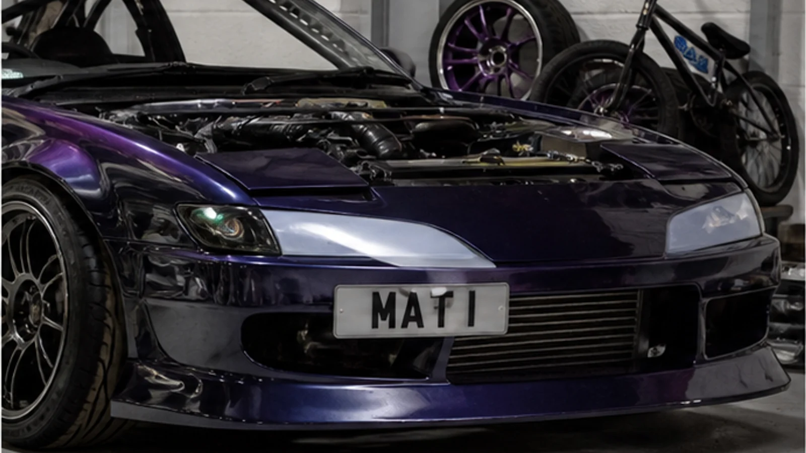 Modified sports car in a workshop with Mat Armstrong-inspired number plate